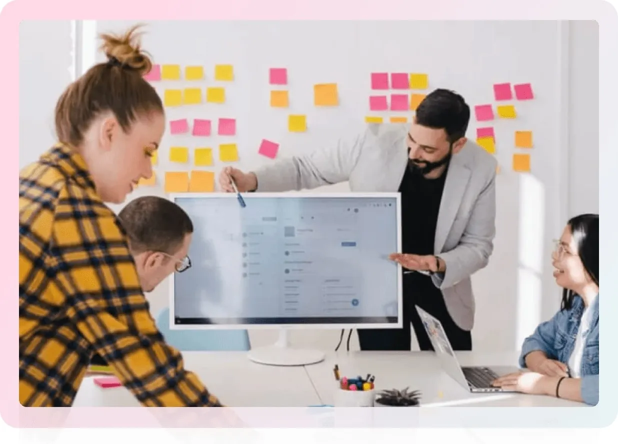 A group of people in a meeting room with sticky notes on the wall, brainstorming ideas.