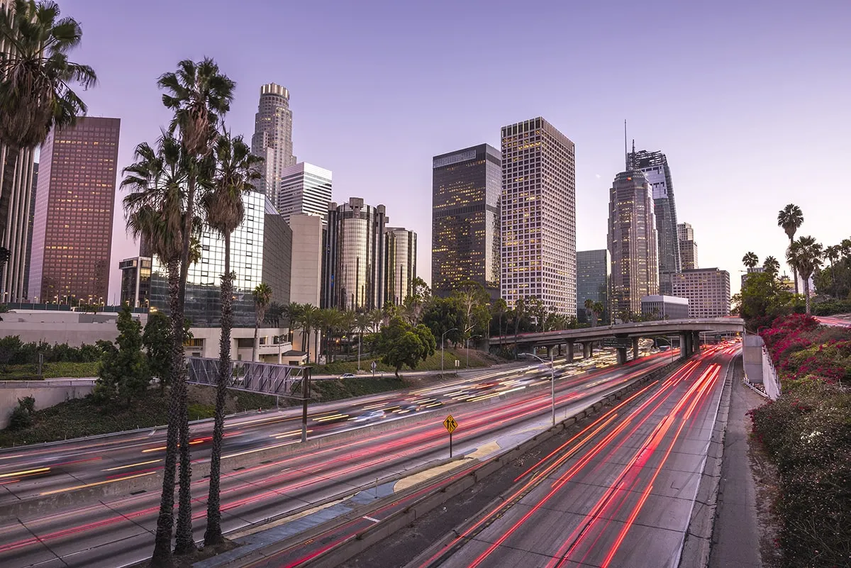 The city of Los Angeles at dusk with palm trees in the background, showcasing its vibrant atmosphere.