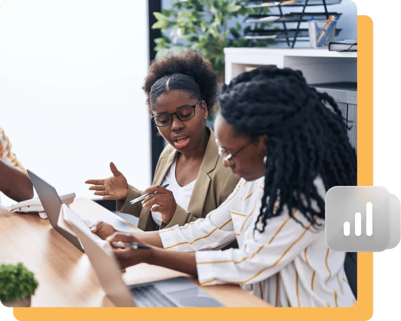 Two women collaborating on laptops in an office setting, discussing data or a project, with a bar graph icon overlay representing analytics or performance