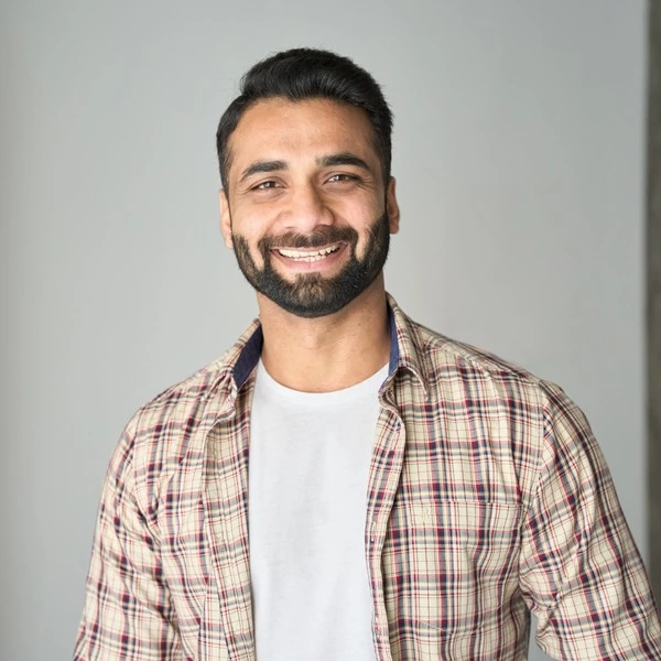 A smiling man with a beard wearing a plaid shirt, embodying the essence of Local SEO.