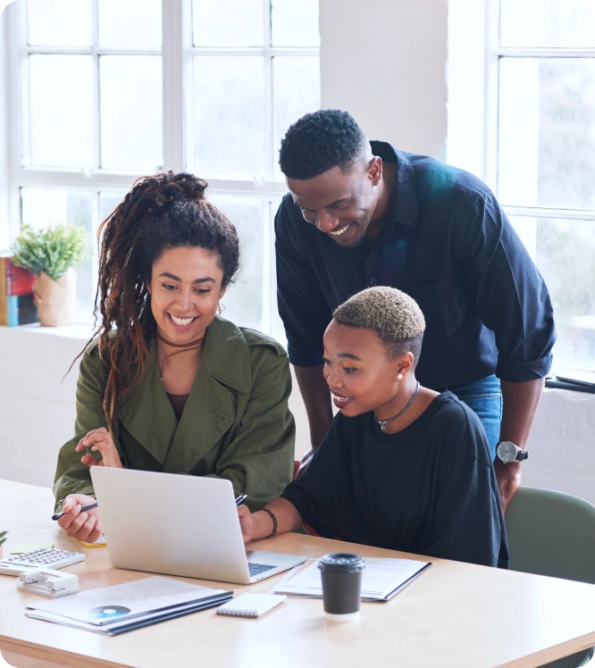 Three people collaborate at a desk with a laptop, smiling and discussing Local SEO Services displayed on the screen in a bright office space.
