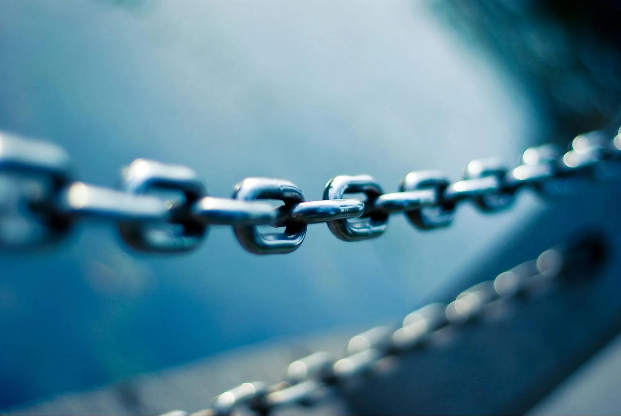 Close-up image of a metal chain in focus with a blurred blue-toned background, symbolizing connection, strength, or linking concepts such as backlinks in SEO