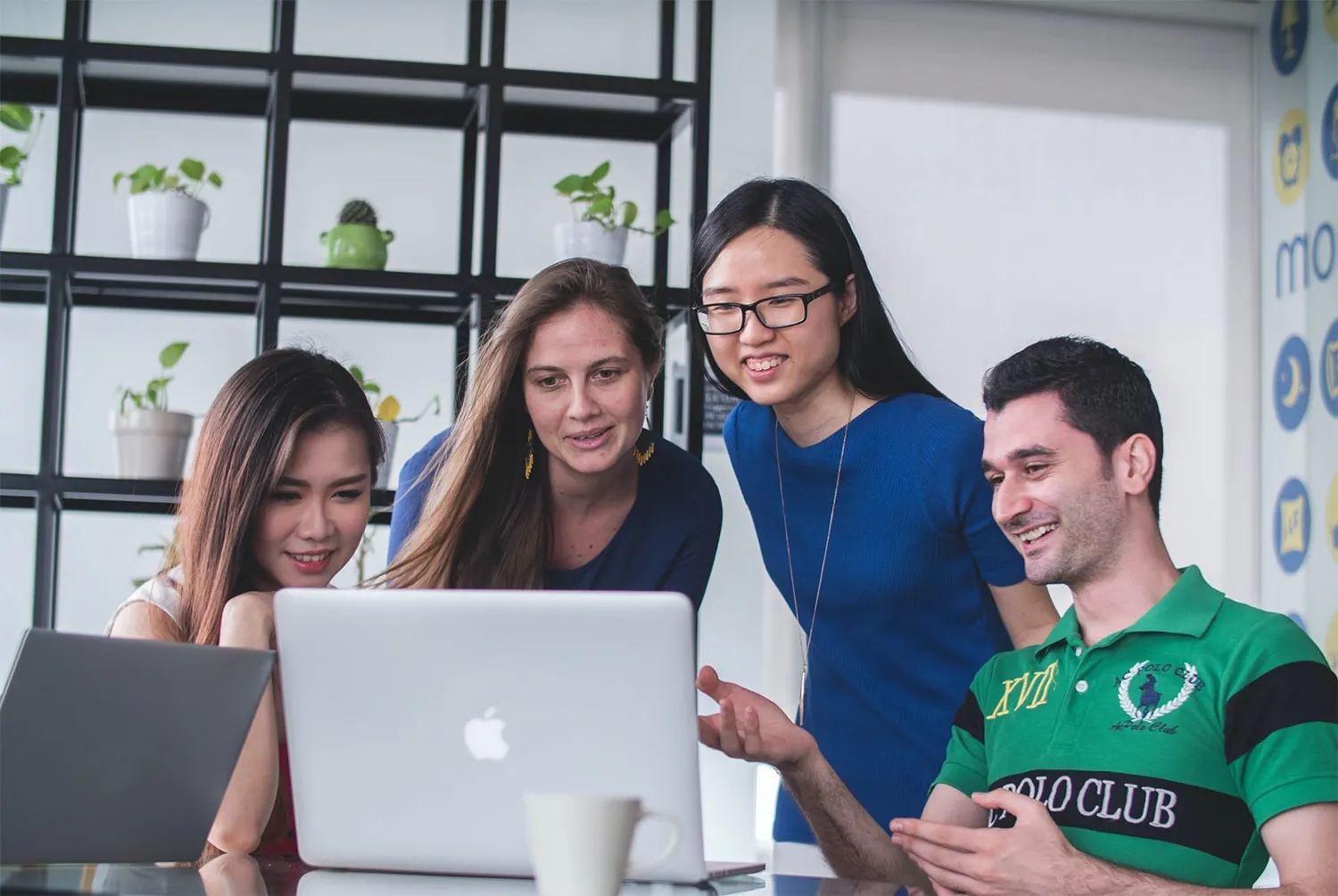 Diverse group of young professionals collaborating around a laptop in a modern office setting